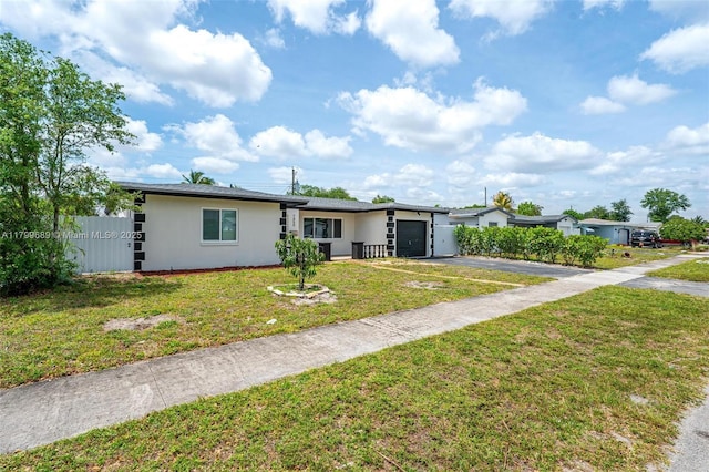 7450 Branch St, Hollywood, FL 33024 - view of front of home with asphalt driveway, a garage, stucco siding, and a front yard