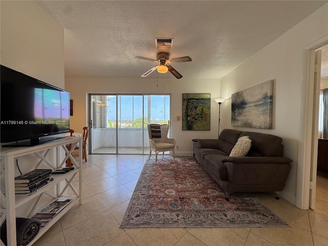 living area with light tile patterned floors, ceiling fan, and a textured ceiling
