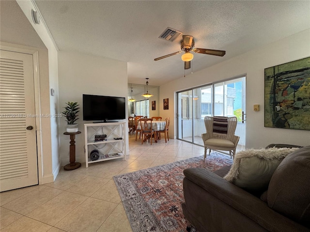 living room with light tile patterned floors, a ceiling fan, a textured ceiling, and baseboards