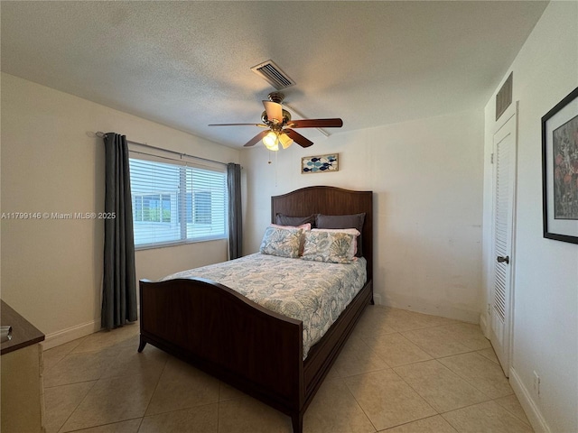 bedroom with light tile patterned floors, ceiling fan, and a textured ceiling