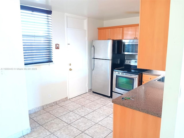 3703 NE 166th St Unit 704, North Miami Beach, FL 33160 - kitchen with appliances with stainless steel finishes, dark countertops, light brown cabinets, light tile patterned floors, and baseboards