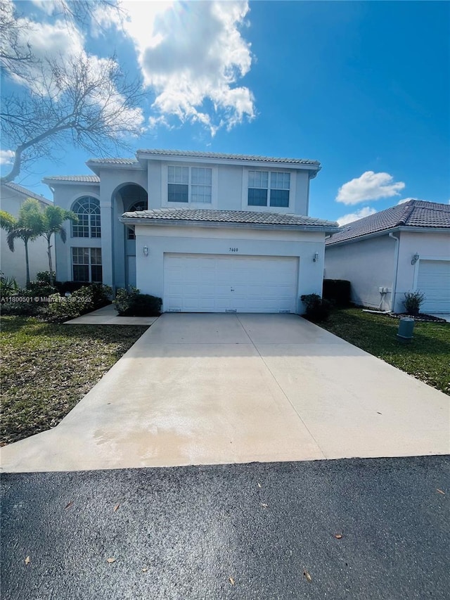 view of front of home with concrete driveway, stucco siding, a tiled roof, and a garage