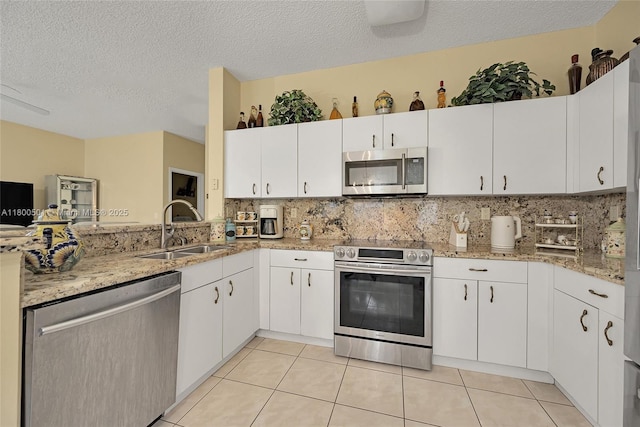 7600 Belmonte Blvd, Margate, FL 33063 - kitchen featuring appliances with stainless steel finishes, backsplash, light stone counters, white cabinetry, and a textured ceiling