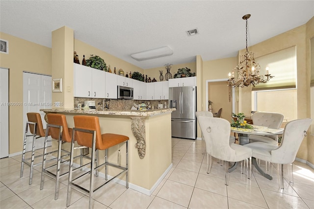 7600 Belmonte Blvd, Margate, FL 33063 - kitchen with stainless steel appliances, a chandelier, backsplash, a peninsula, and a kitchen breakfast bar