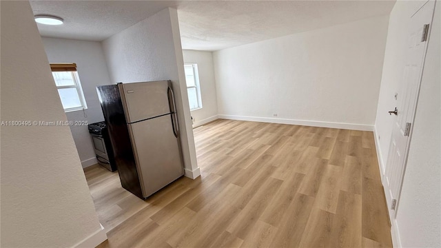 7334 Harding Ave Unit 3, Miami Beach, FL 33141 - kitchen with appliances with stainless steel finishes, a textured wall, light wood-style floors, baseboards, and a textured ceiling