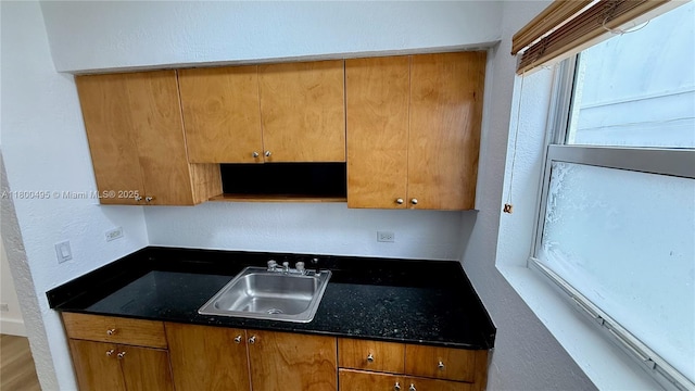 7334 Harding Ave Unit 3, Miami Beach, FL 33141 - kitchen with a sink, brown cabinets, a textured wall, and dark stone countertops