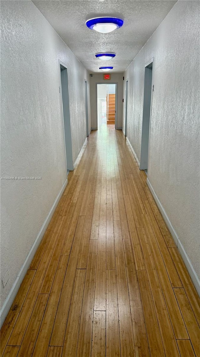 7334 Harding Ave Unit 3, Miami Beach, FL 33141 - hall featuring a textured wall, light wood-style flooring, baseboards, and a textured ceiling