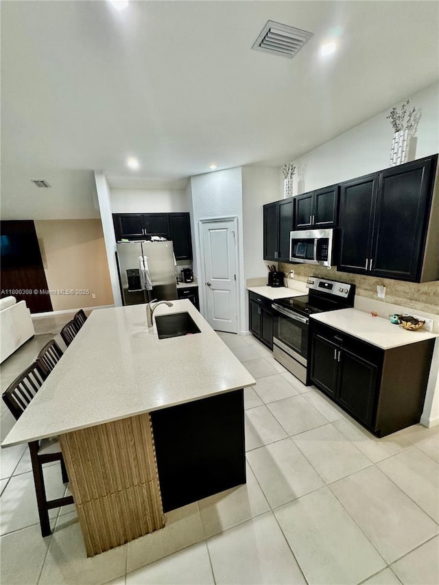 kitchen with appliances with stainless steel finishes, dark cabinetry, a sink, backsplash, and recessed lighting