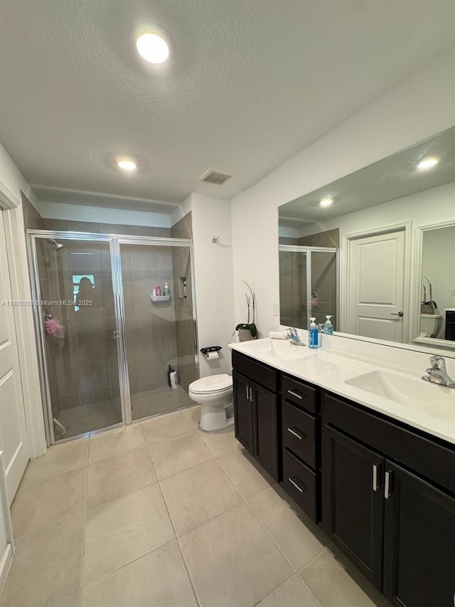 full bath with a shower stall, double vanity, toilet, tile patterned floors, and a textured ceiling