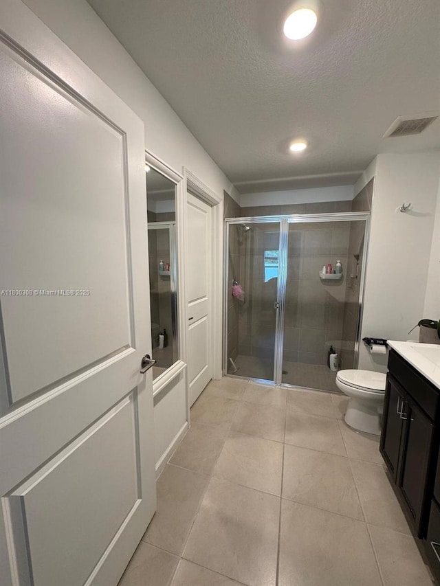 full bath featuring a stall shower, vanity, a textured ceiling, tile patterned flooring, and toilet
