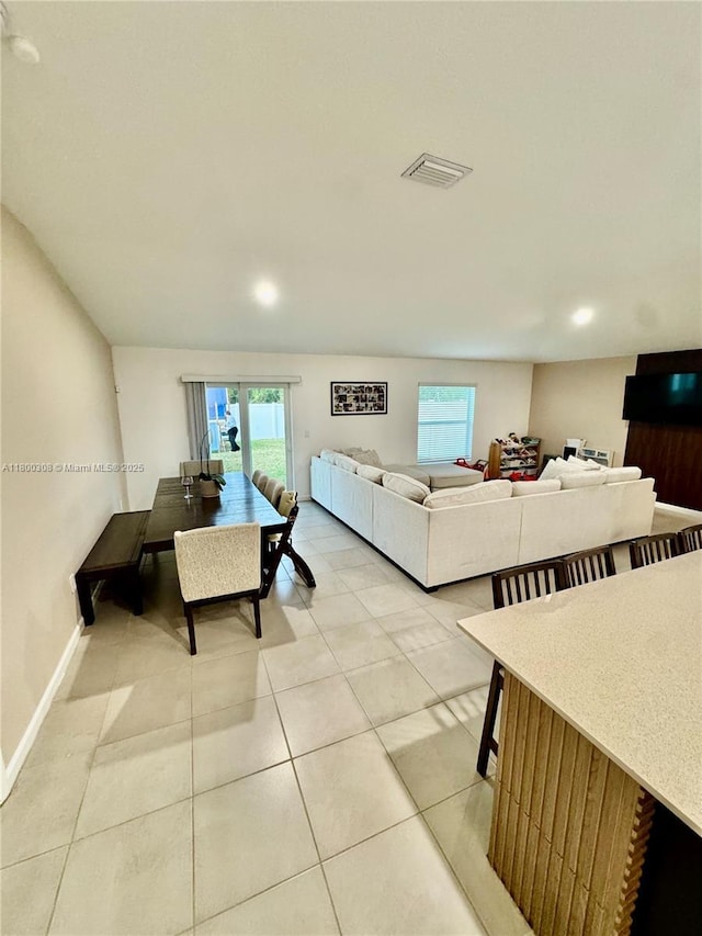 living room featuring plenty of natural light, light tile patterned flooring, baseboards, and recessed lighting
