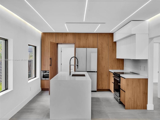 4921 NW 6th Ave, Miami, FL 33127 - kitchen featuring modern cabinets, appliances with stainless steel finishes, light countertops, white cabinetry, and an island with sink