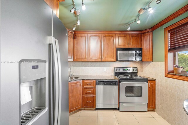 4800 Hillcrest Ln Unit 503, Hollywood, FL 33021 - kitchen featuring stainless steel appliances, light tile patterned floors, rail lighting, brown cabinetry, and tile walls