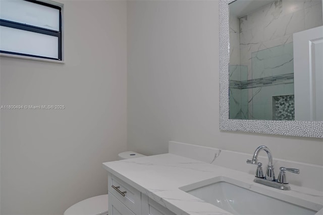 full bath with vanity, a marble finish shower, and toilet
