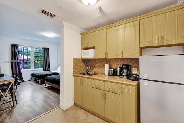 kitchen with white appliances, a sink, tasteful backsplash, light countertops, and crown molding
