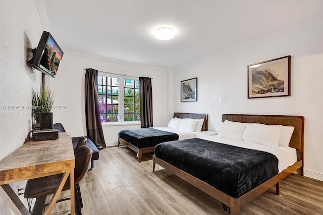 bedroom with wood finished floors, crown molding, and baseboards