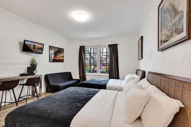 bedroom with ornamental molding and wood finished floors