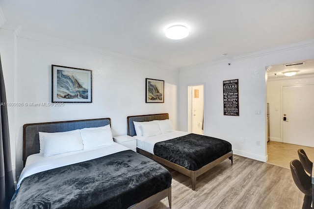 bedroom with ornamental molding, light wood-style flooring, and baseboards