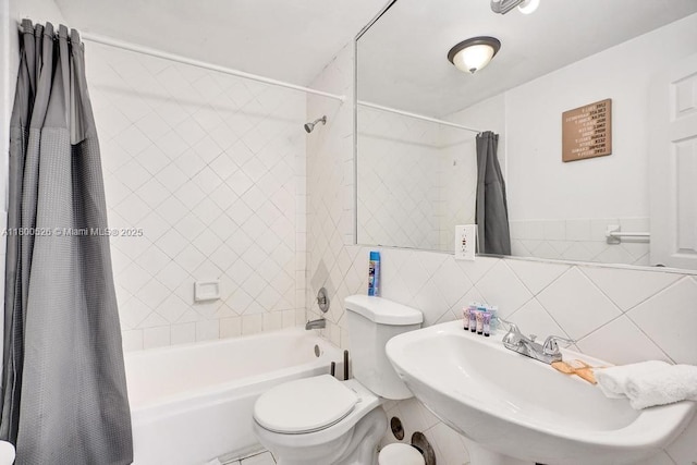 full bath with a sink, tile walls, toilet, and shower / bath combination with curtain