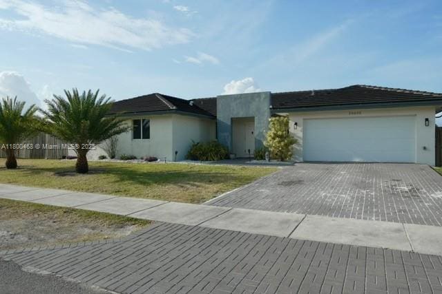 20600 SW 316th St, Homestead, FL 33030 - ranch-style home with decorative driveway, stucco siding, an attached garage, and a front yard