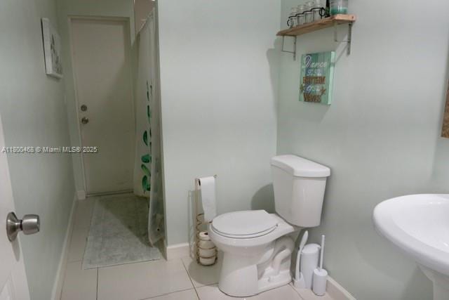 20600 SW 316th St, Homestead, FL 33030 - full bathroom with a shower with curtain, toilet, tile patterned floors, baseboards, and a sink