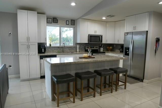 20600 SW 316th St, Homestead, FL 33030 - kitchen with appliances with stainless steel finishes, a sink, decorative backsplash, a center island, and light stone counters
