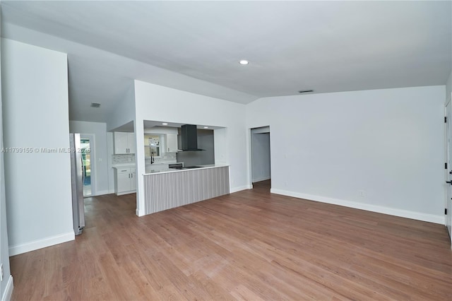 unfurnished living room featuring vaulted ceiling, light wood-style floors, baseboards, and recessed lighting