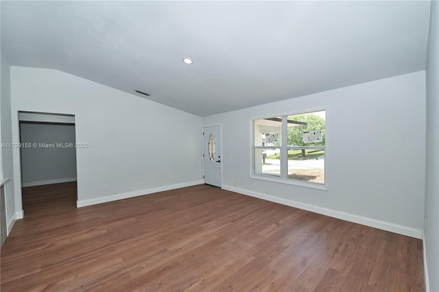 unfurnished living room with lofted ceiling, wood finished floors, and baseboards