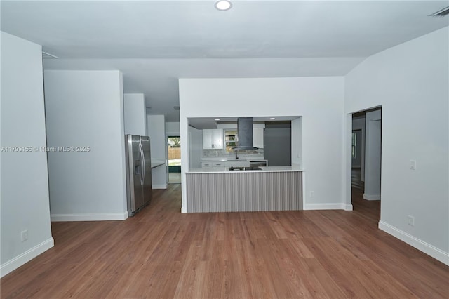 kitchen with stainless steel refrigerator with ice dispenser, light countertops, wood finished floors, and baseboards