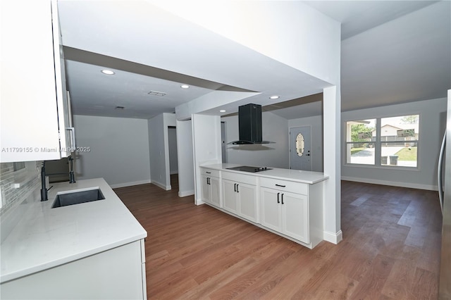 kitchen with exhaust hood, a sink, light wood finished floors, white cabinets, and baseboards