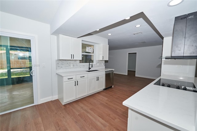 kitchen with stainless steel dishwasher, baseboards, a sink, black electric stovetop, and white cabinetry