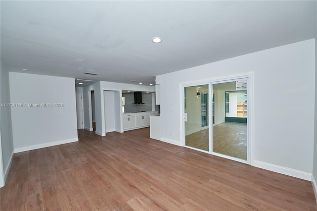unfurnished living room featuring light wood-style flooring, baseboards, and recessed lighting