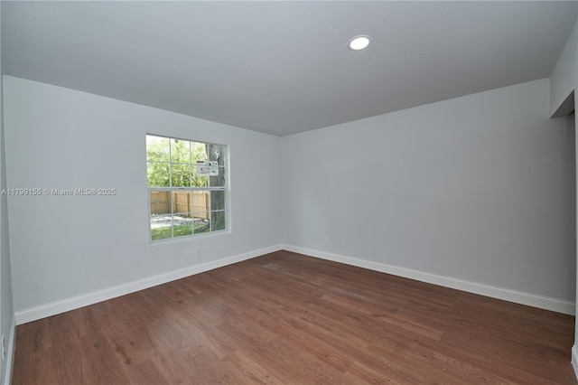 spare room with baseboards, dark wood-type flooring, and recessed lighting