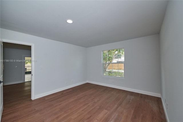 empty room with baseboards, healthy amount of natural light, dark wood-type flooring, and recessed lighting