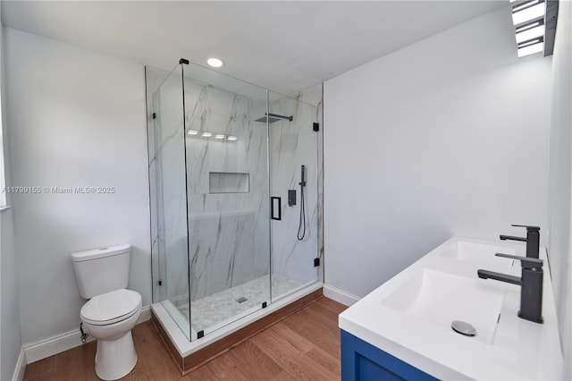 bathroom featuring toilet, a marble finish shower, wood finished floors, and recessed lighting