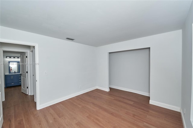 unfurnished bedroom with wood finished floors, baseboards, and a closet