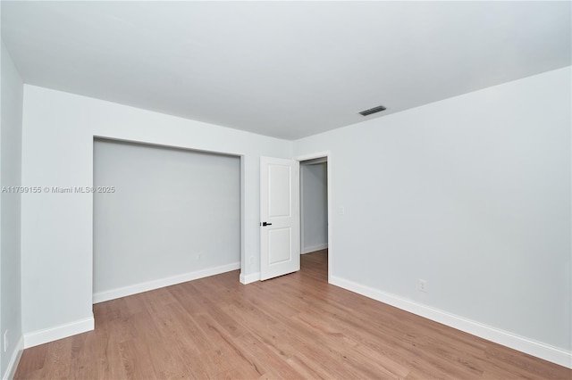 unfurnished bedroom with light wood-type flooring, baseboards, and a closet