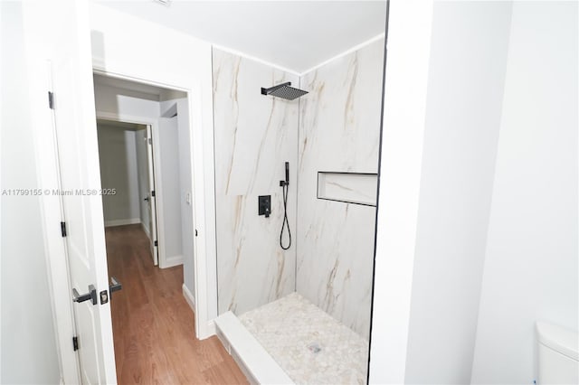 bathroom with a marble finish shower, wood finished floors, and toilet