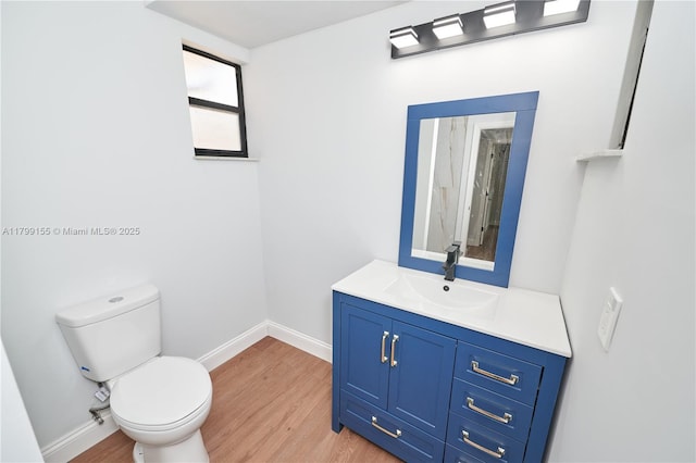 full bathroom featuring wood finished floors, toilet, baseboards, and vanity
