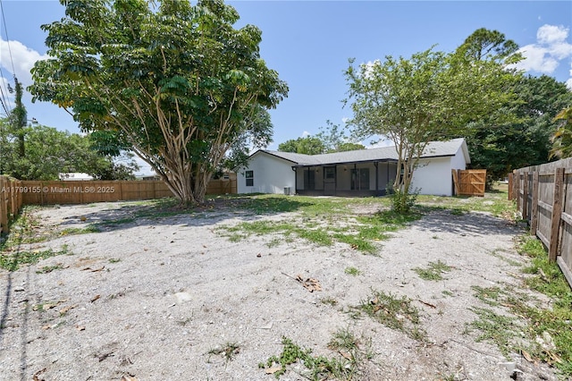 back of house with a sunroom, a fenced backyard, and stucco siding