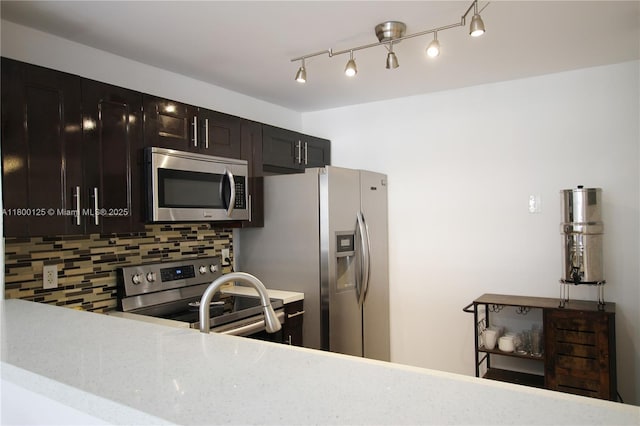 kitchen featuring stainless steel appliances, backsplash, and light stone countertops