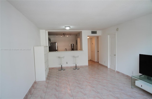 unfurnished living room featuring track lighting and light tile patterned floors
