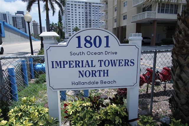community / neighborhood sign featuring fence and a city view
