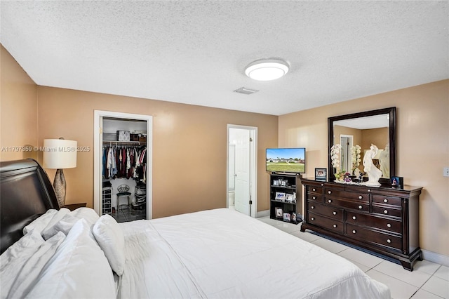 707 W 39th Pl, Hialeah, FL 33012 - bedroom featuring light tile patterned floors, a textured ceiling, a spacious closet, a closet, and ensuite bathroom