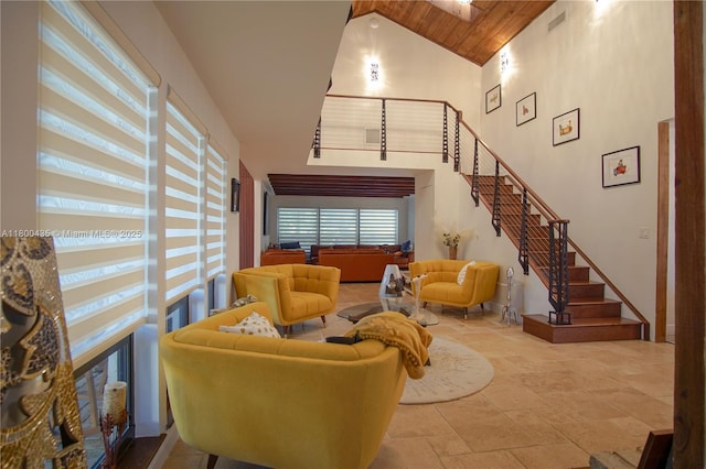 living room featuring high vaulted ceiling, stairs, and stone tile floors