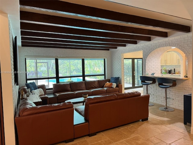 living area with brick wall and beam ceiling