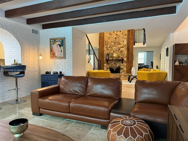 living room with beamed ceiling, stairway, wood finished floors, and brick wall