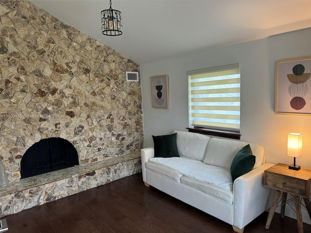 living room with vaulted ceiling, wood finished floors, and a stone fireplace