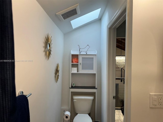 bathroom with a skylight, lofted ceiling, and toilet