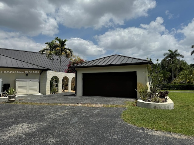 view of front of home featuring a standing seam roof, driveway, metal roof, an attached garage, and stucco siding